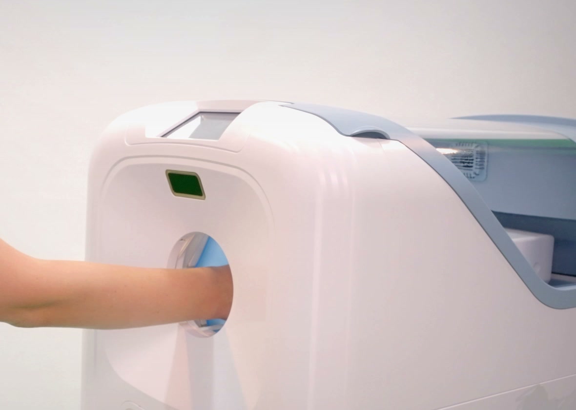 A gloved hand entering the IGIN® hand window — touch-free dispensing